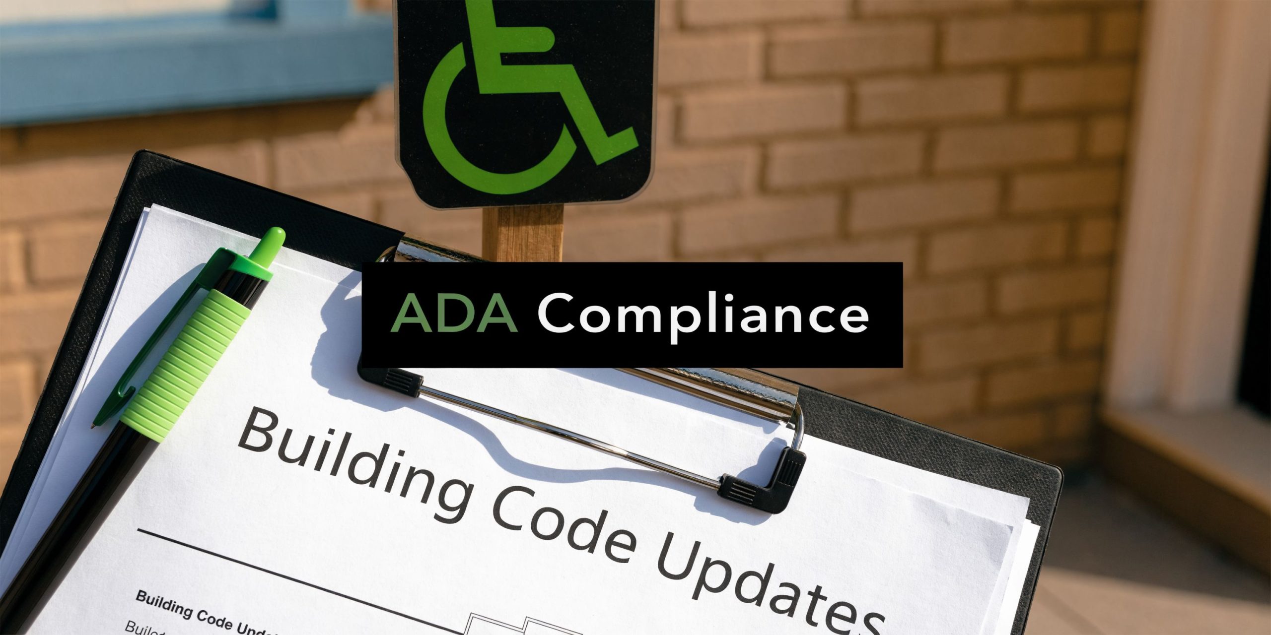 A clipboard with building code updates and an ADA compliance sign against a brick building background.