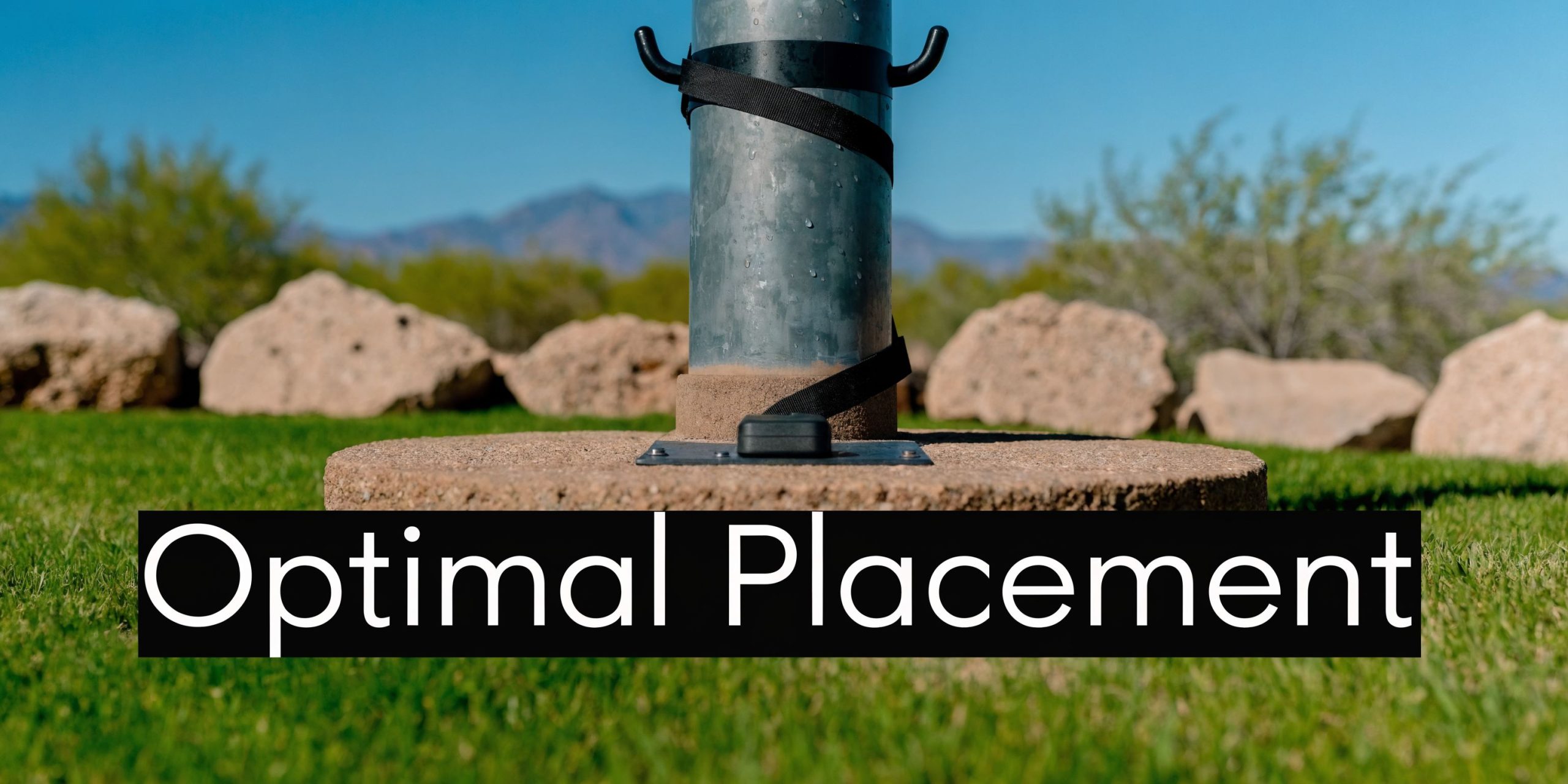 A close-up view of a metal pole base on a concrete platform in a desert landscape.