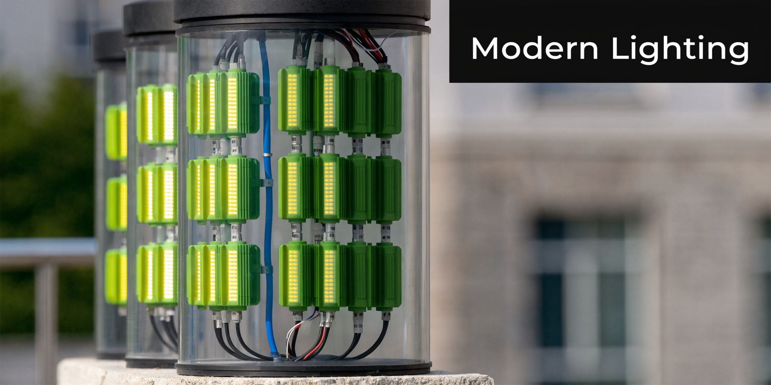A close-up view of modern cylindrical street lights with illuminated green LED modules inside clear housing.