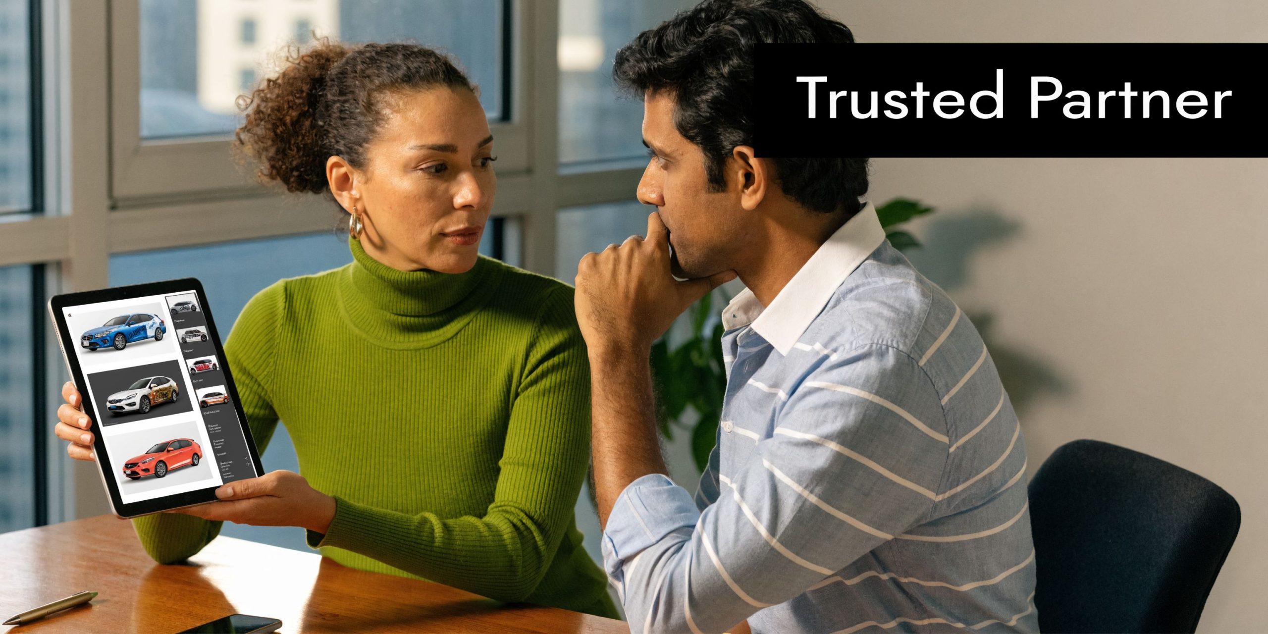 A professional woman showing a digital catalog of vehicle wraps on a tablet to a male colleague.